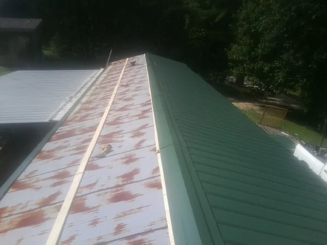 Old rusted panels beside newly installed green metal roofing — Wind Damage Roof Repair by Roofing Brothers in Mount Gilead