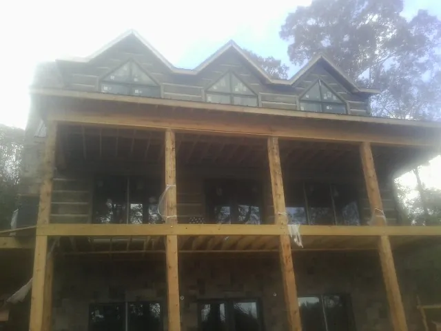 Dormers and porch framing on a large log home under construction — Roof Coating work by our crew in Mount Gilead