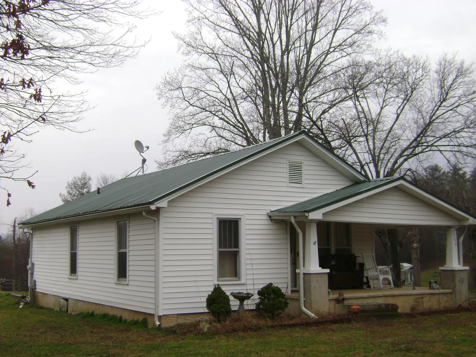 Green metal roof on a white bungalow with a side porch in Mount Gilead