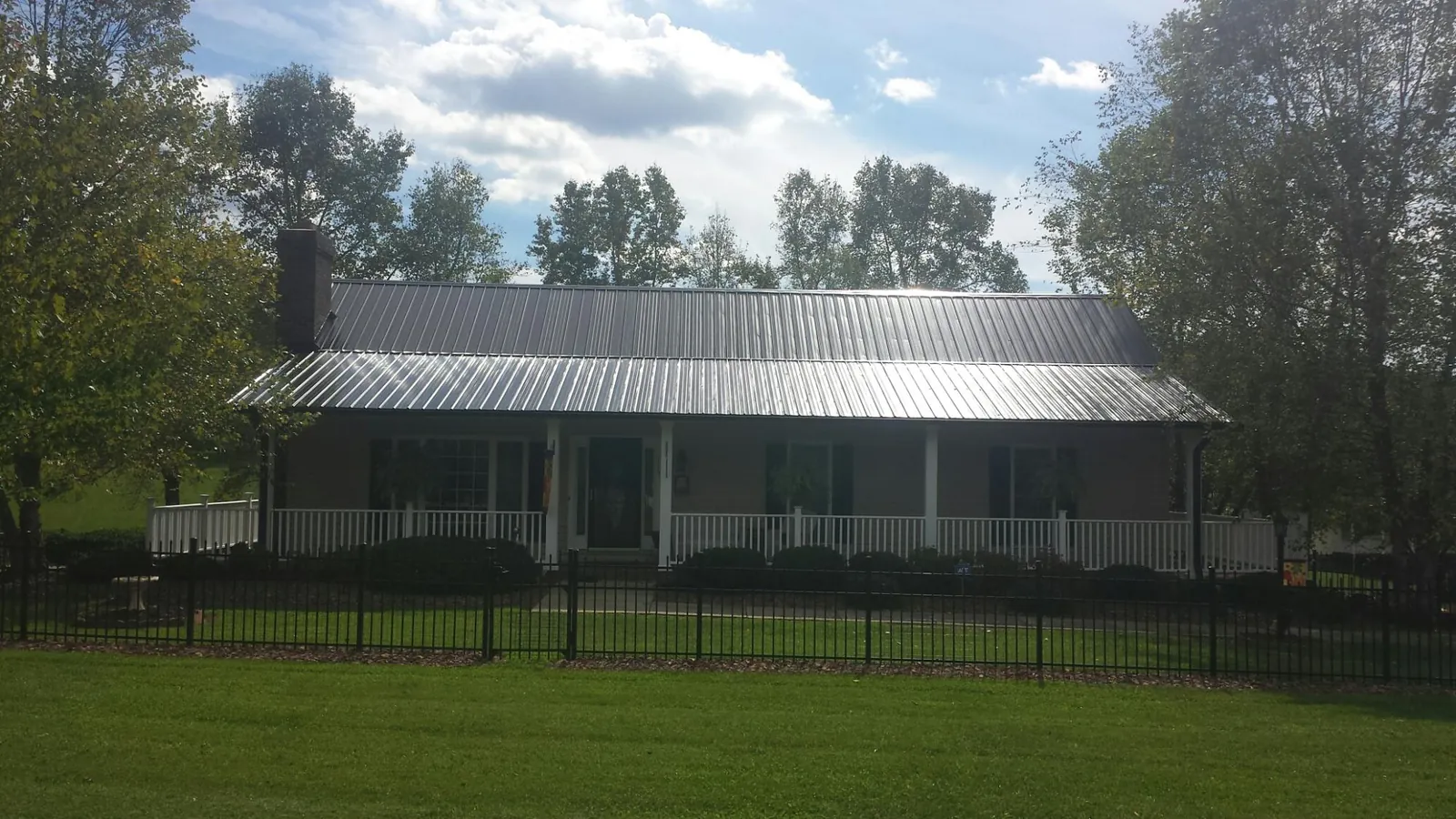 Gray metal roof on a brick ranch with a full width front porch — Gutter Guard Installation work by our crew in Mount Gilead