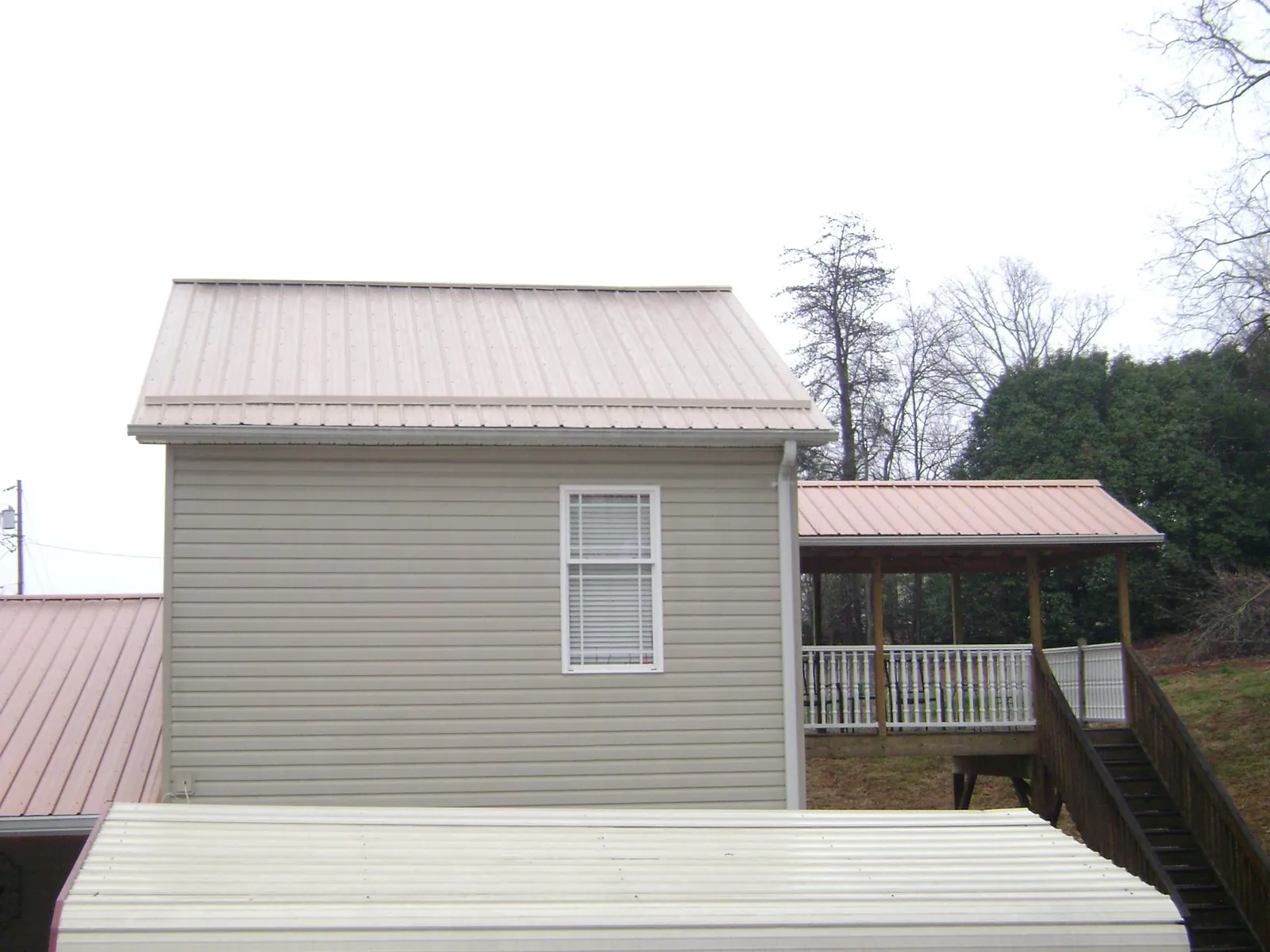 Tan metal roofs on a two story addition and attached porch, from a Roof Replacement job in Mount Gilead